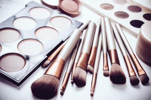 Makeup and makeup brushes spread out on table 