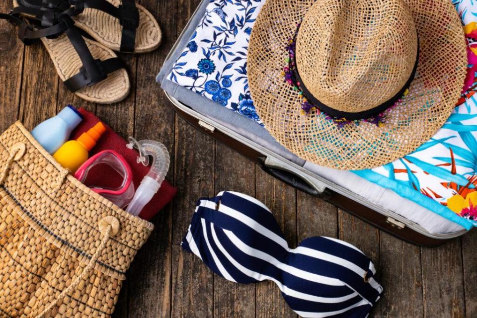 A suitcase sits open full of summer vacation items. 