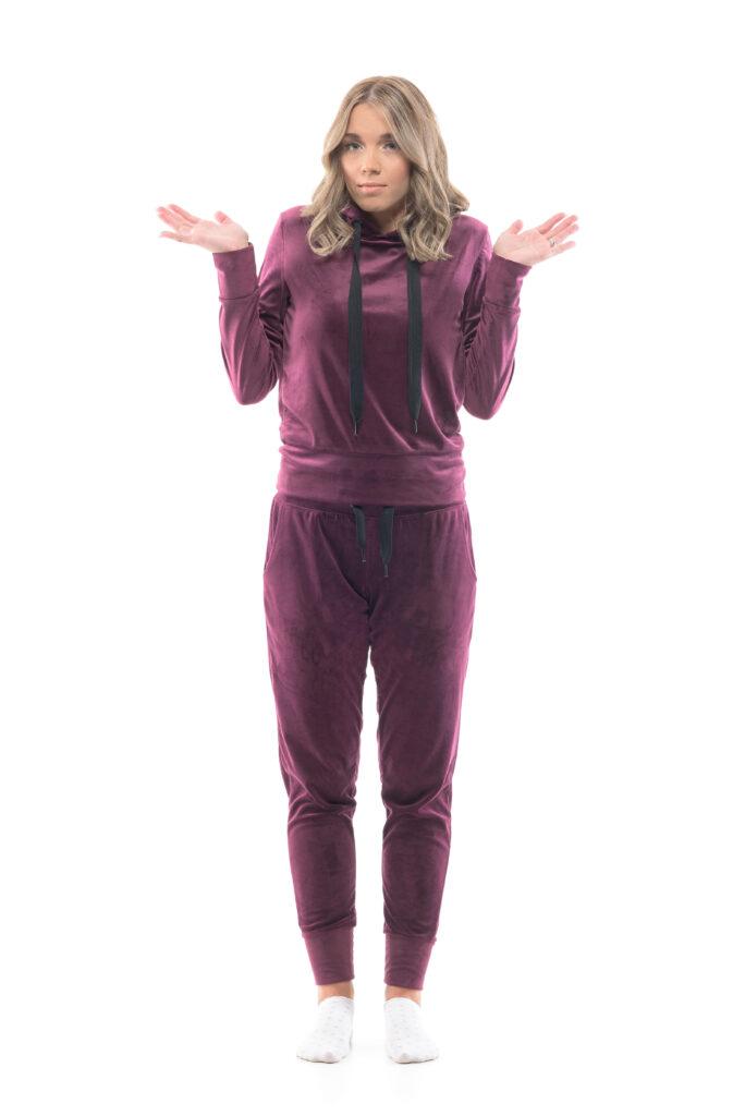 A woman in a purple sweatsuit stands looking confused. This is an image on a blog entitled "Why Wearing Your Covid-Era Sweatpants Is Affecting Your Professional Image".